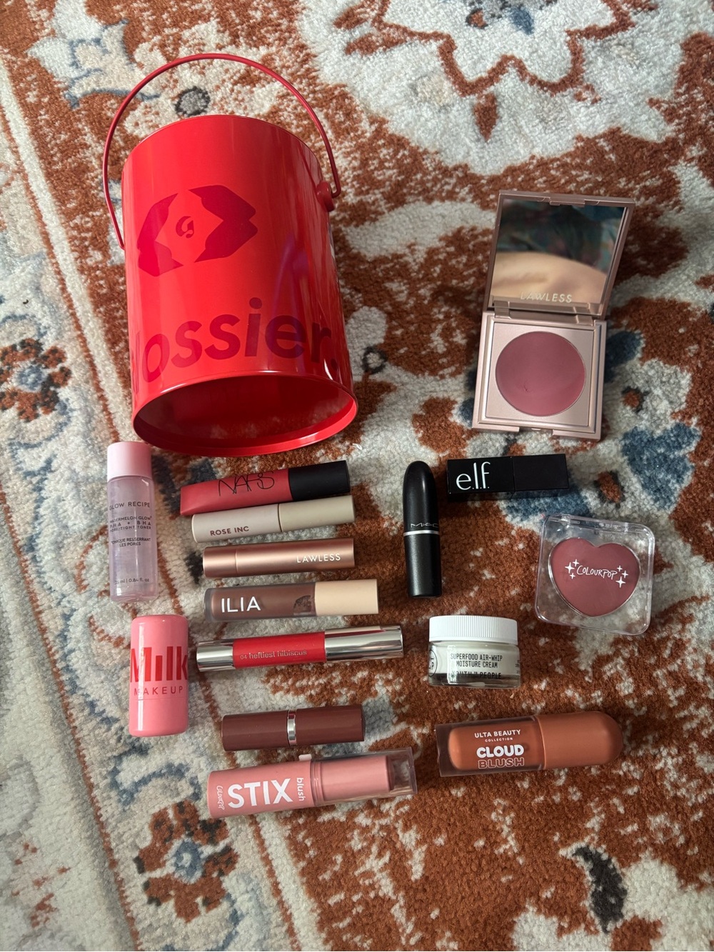 Glossier red mini bucket with mixed pink and mauve lip products